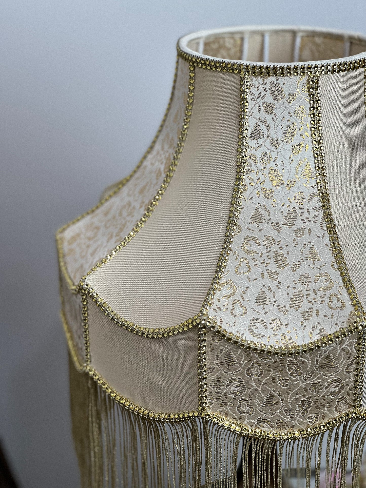 Gold-colored table lamp with elegant lace details and tasseled fringe. 7202