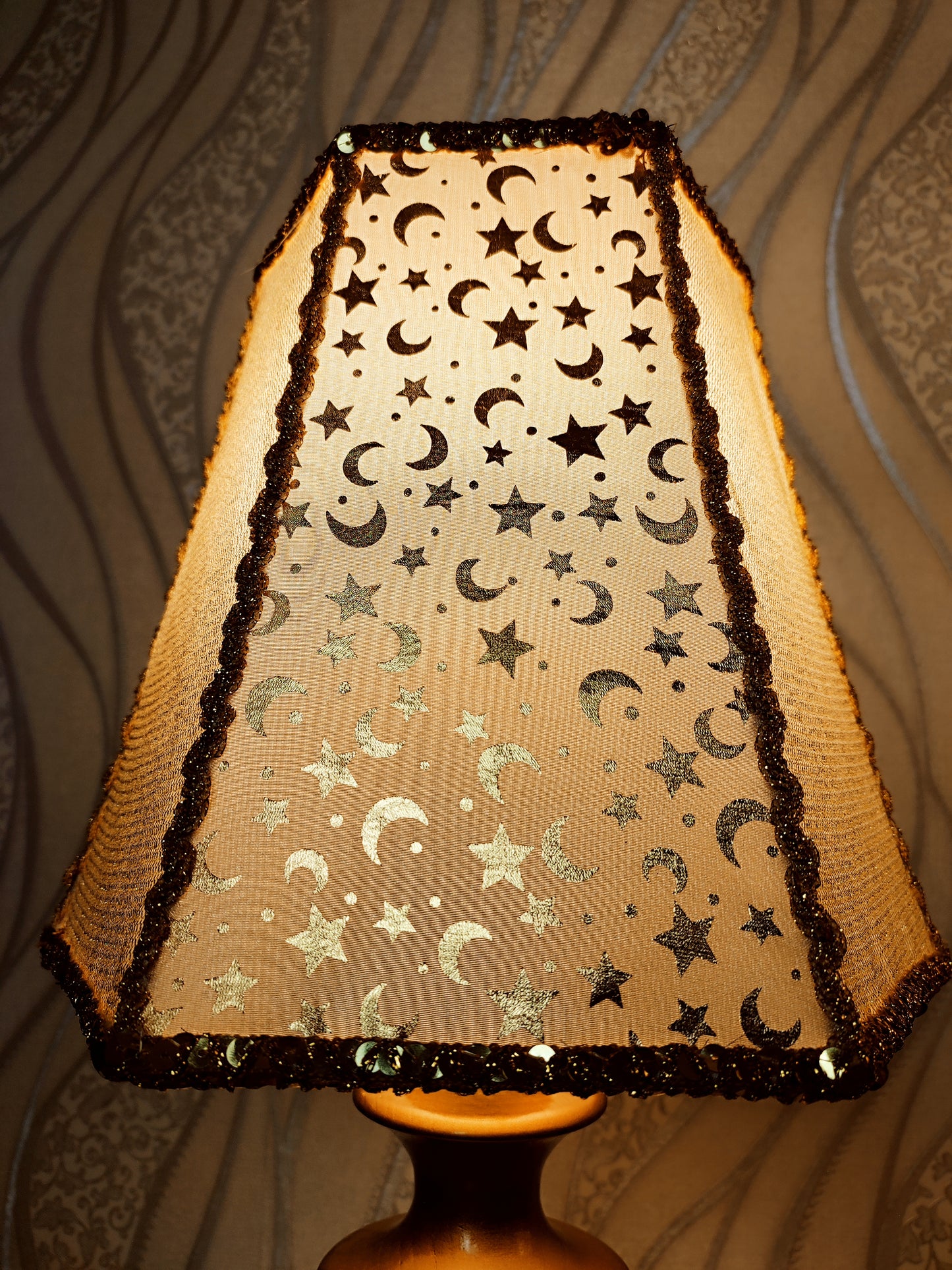 Table lamp. Golden celestial lamp with shimmering moons and stars on a delicate fabric. The wooden base is bronze in color. 7701