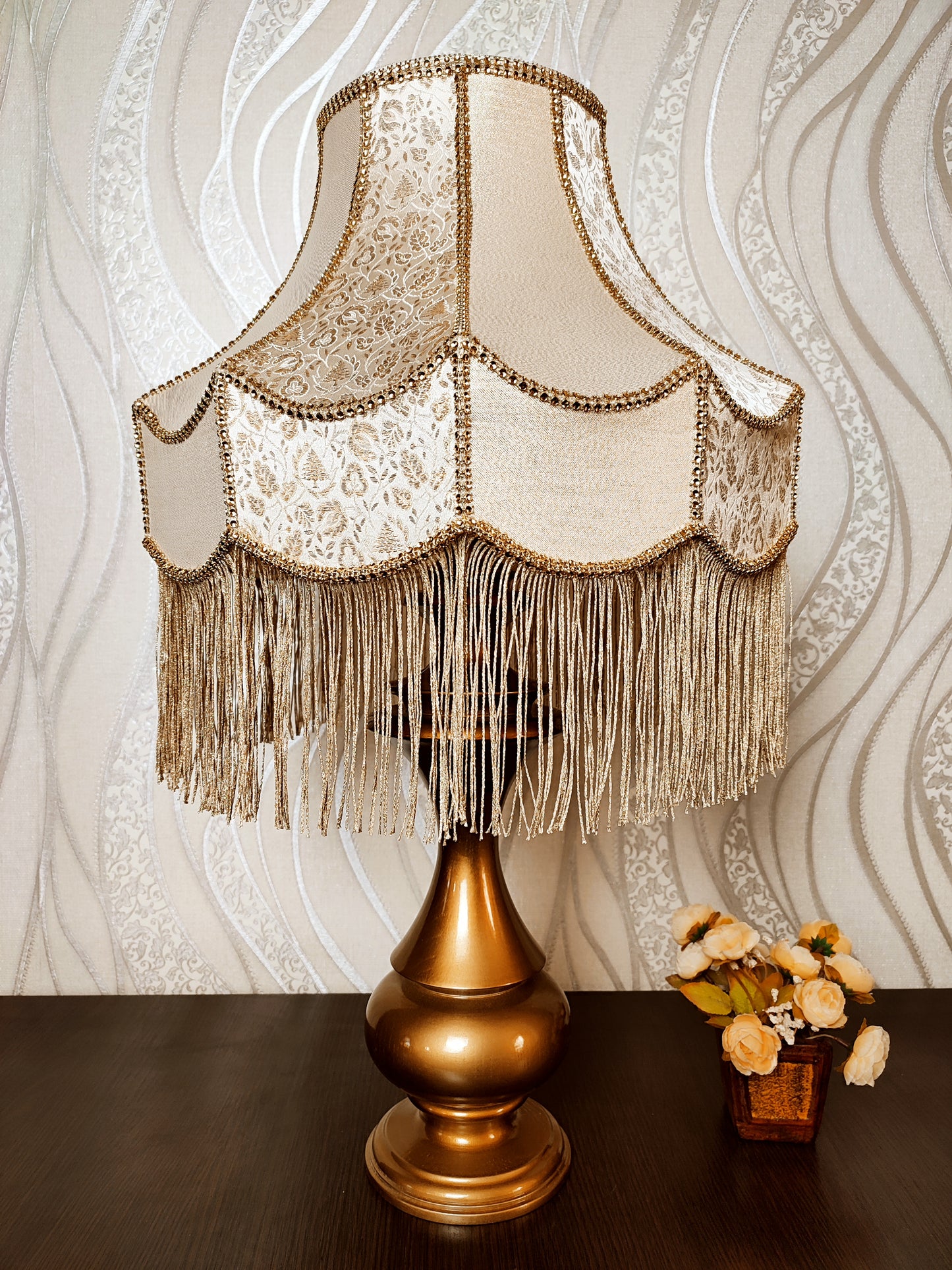 Gold-colored table lamp with elegant lace details and tasseled fringe. 7202