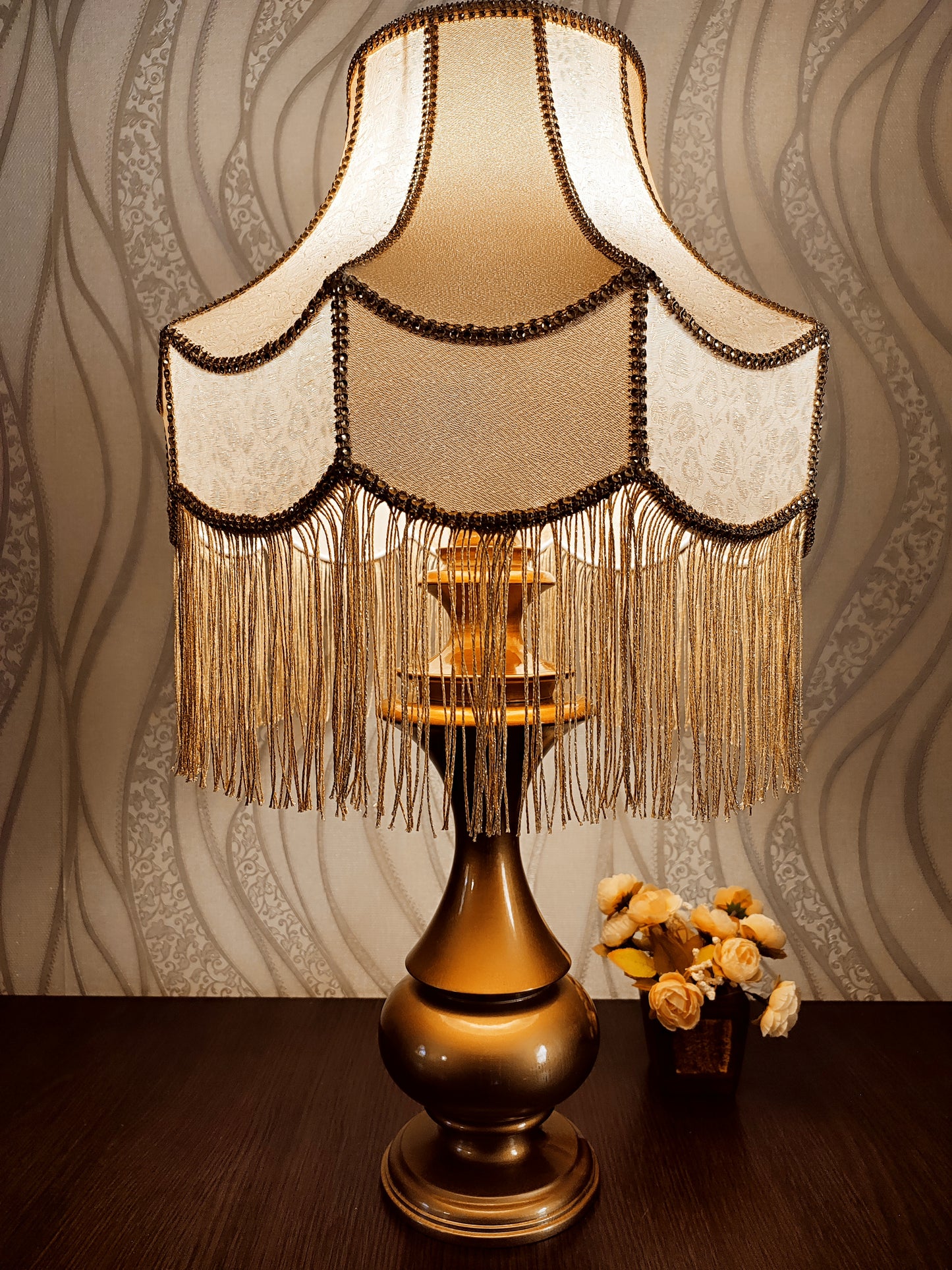 Gold-colored table lamp with elegant lace details and tasseled fringe. 7202