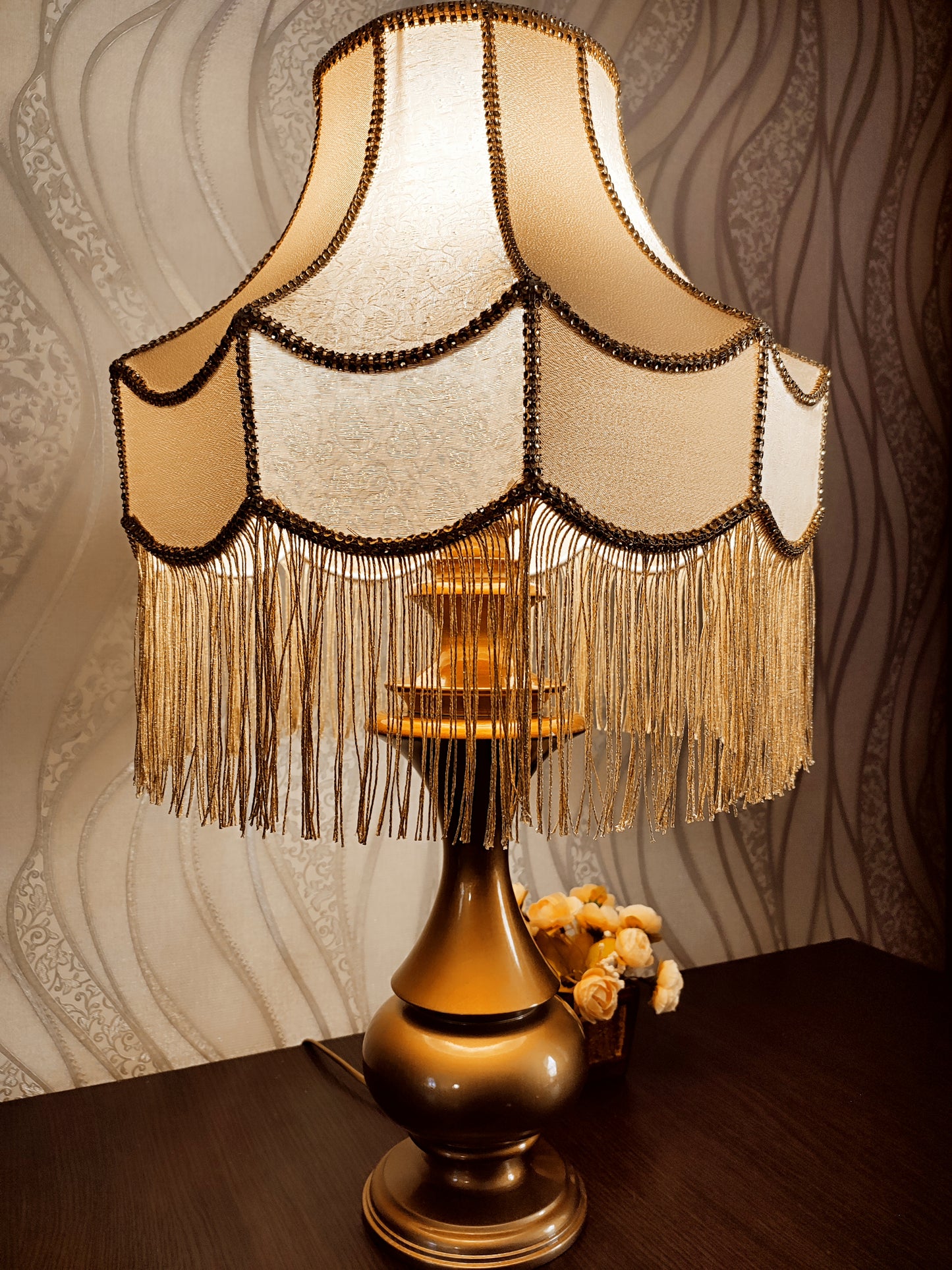 Gold-colored table lamp with elegant lace details and tasseled fringe. 7202