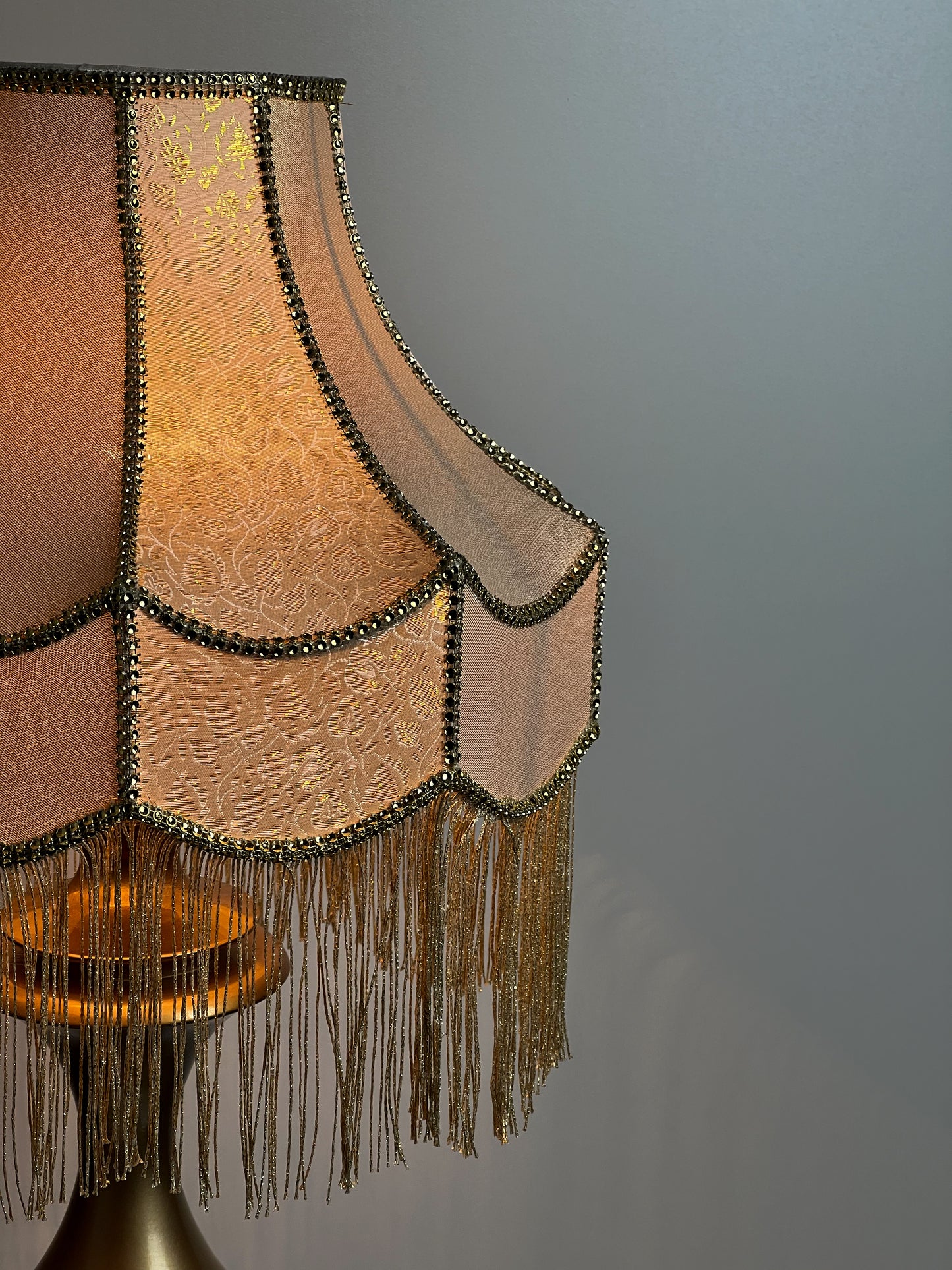 Gold-colored table lamp with elegant lace details and tasseled fringe. 7202