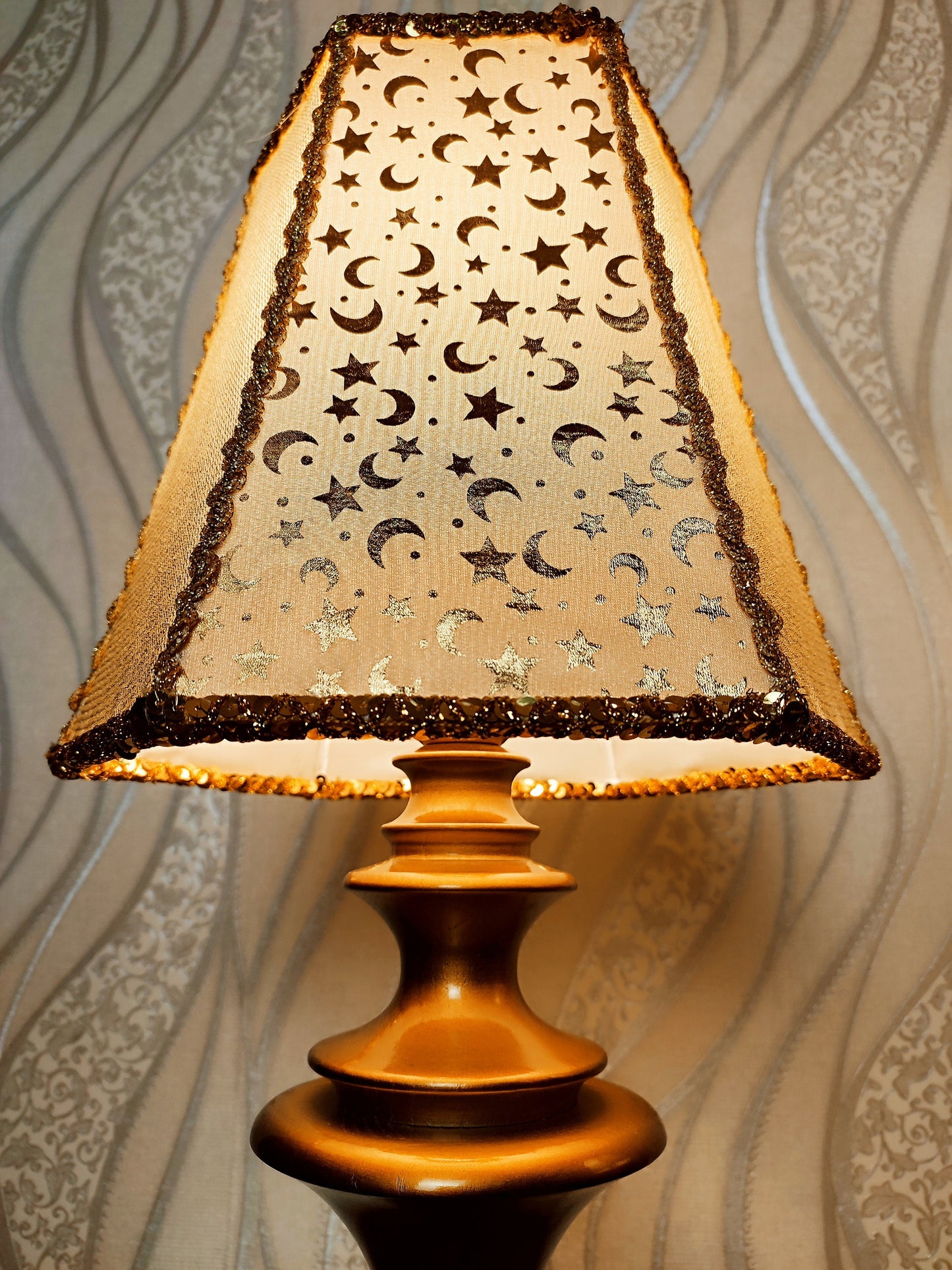 Table lamp. Golden celestial lamp with shimmering moons and stars on a delicate fabric. The wooden base is bronze in color. 7701