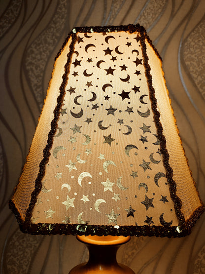 Table lamp. Golden celestial lamp with shimmering moons and stars on a delicate fabric. The wooden base is bronze in color. 7701