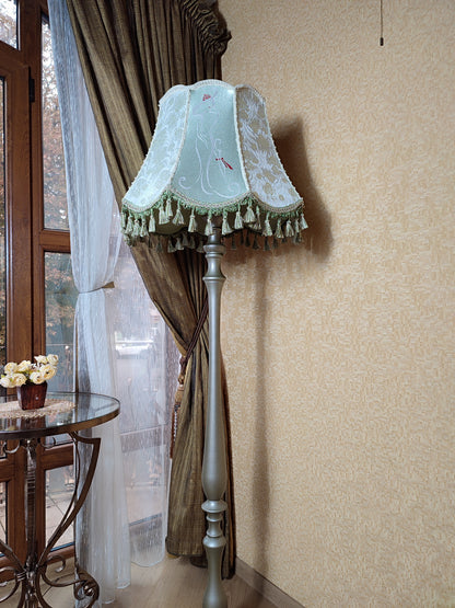 A Victorian floor lamp with a fabric shade and an exquisite floral umbrella motif with tassels.