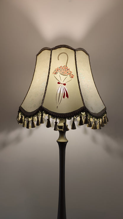 A Victorian floor lamp with a fabric shade and an exquisite floral umbrella motif with tassels.