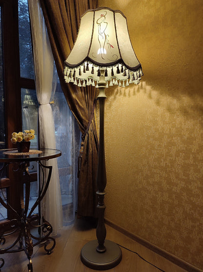 A Victorian floor lamp with a fabric shade and an exquisite floral umbrella motif with tassels.