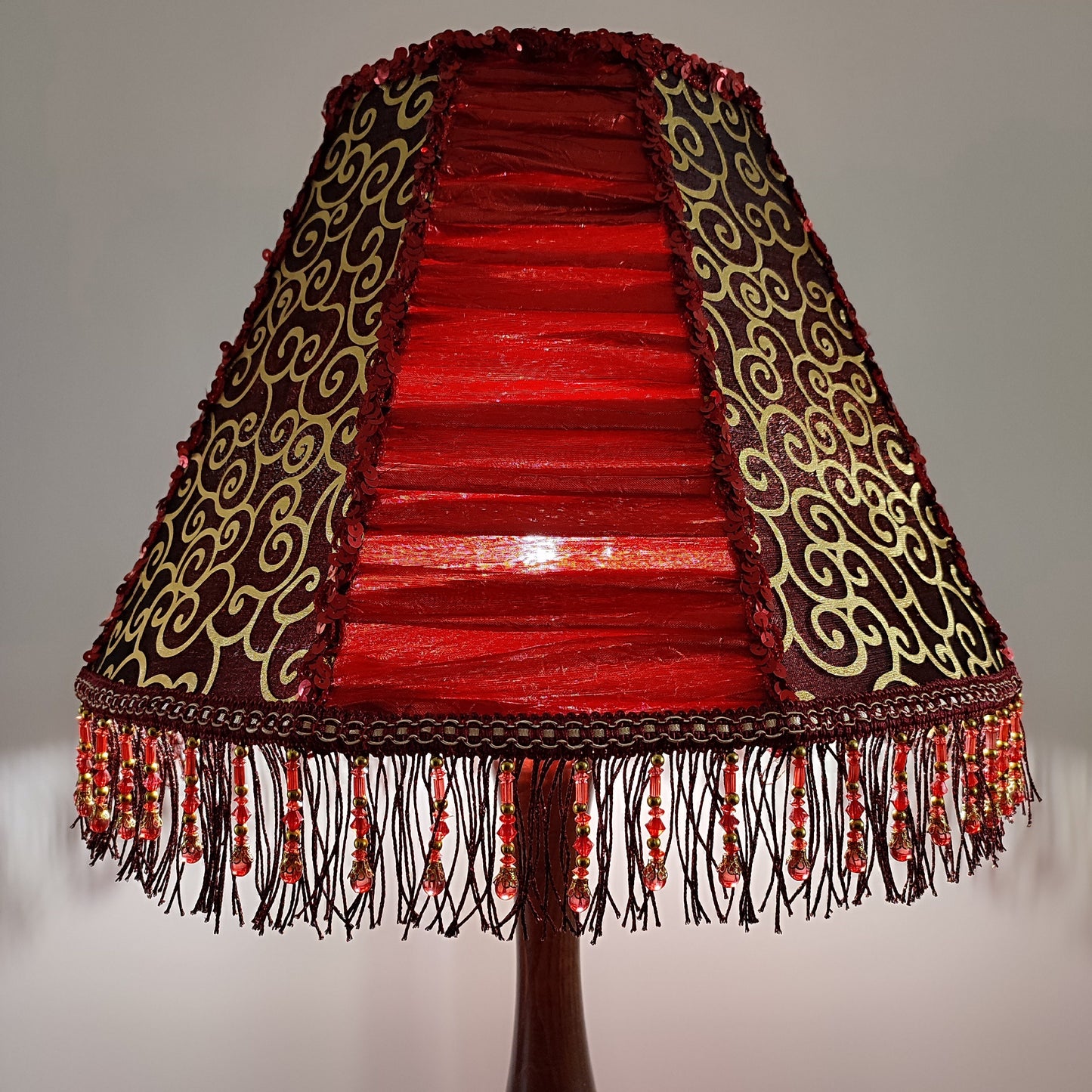 A burgundy lampshade with a swirling pattern and beaded fringe.Unique lamp, handcrafted laтббmp, decorative lamp. 1116